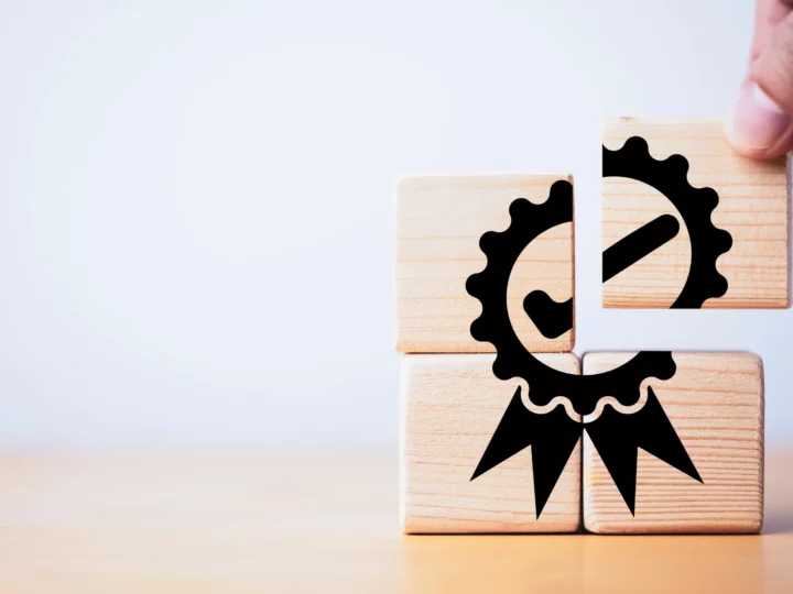 A person stacking wooden cubes making a certification symbol.
