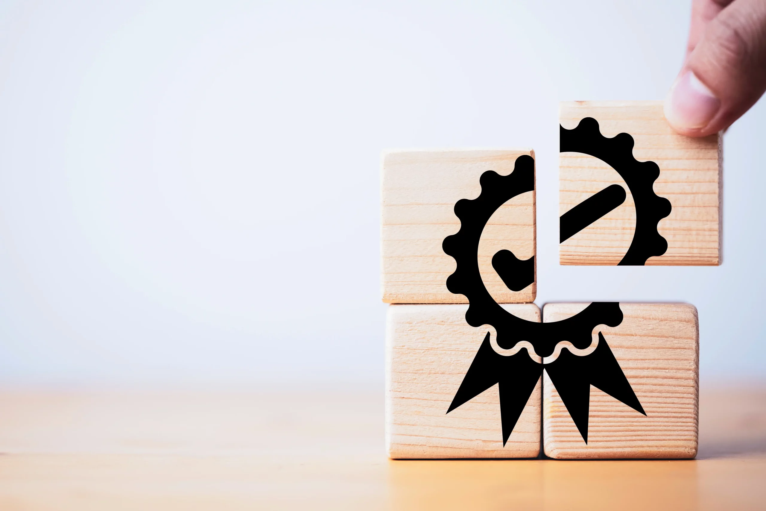 A person stacking wooden cubes making a certification symbol.